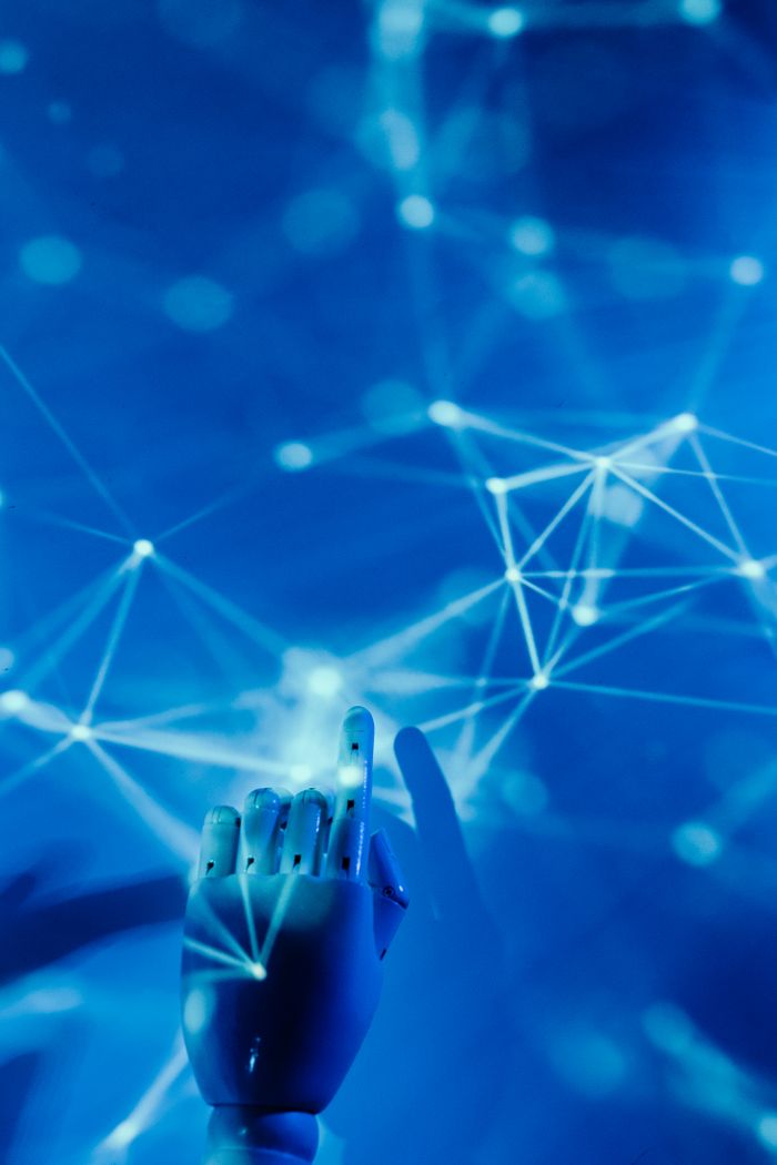 Home Futuristic robotic hand touching a digital network on a blue background.